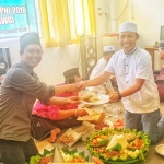 Ketua KWG M. Syuhud Almanfaluty menyerahkan potongan tumpeng kepada Ketua Panitia HPN KWG 2019, Khanif Rosyidi.