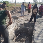 Warga Desa Pecanggaan gotong royong memperbaiki jembatan yang ambruk.