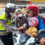 Anggota Satlantas Polres Mojokerto Kota saat membagikan coklat kepada para pengguna jalan, Rabu (15/2/2023)