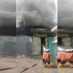 Petugas saat mencoba memadamkan gudang di Margomulyo yang terbakar.