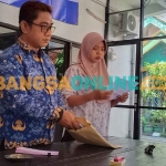 Plt Sekdes Roomo, Achmad Zainul (kiri), saat mengecek tagihan PBB sebelum didistribusikan kepada warga. Foto: SYUHUD/BANGSAONLINE
