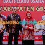 Wakil Bupati Gresik, Aminatun Habibah, didampingi Kepala DPMPTSP Gresik, Agung Endro Dwi Setyo Utomo, ketika menyerahkan penghargaan kepada perwakilan perusahaan. Foto: SYUHUD/BANGSAONLINE