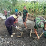 Sumarmi dan Samiyem membantu Satgas TMMD memindahkan pasir.