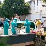 Jenazah korban hendak dimakamkan. Tampak petugas berpakaian APD lengkap.
