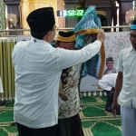 Bupati Pamekasan Baddrut Tamam, memakaikan baju kepada calon jamaah haji.