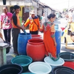 Petugas BPBD Gresik ketika mengisi ember dan bak yang sudah disiapkan warga di salah desa yang dilanda kekeringan. foto: SYUHUD A/BANGSAOLINE
