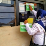 Perangkat desa menempel stiker di dinding rumah warga yang terdaftar PKH. foto: ist.