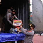 Kapolres Gresik AKBP Mochamad Nur Azis saat menaikkan bantuan ke kontainer. Foto: SYUHUD/ BANGSAONLINE