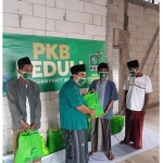 Ketua DPAC Arosbaya, KH. Drs. Moh. Jamhuri saat menyerahkan bantuan  sembako kepada masyarakat terdampak pandemi Covid-19.