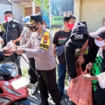 Bonek dan Polresta Sidoarjo saat membagikan masker dan nasi bungkus. (foto: ist).