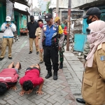 Pengunjung pasar sedang menjalani hukuman push-up karena tidak memakai masker. (foto: ist)