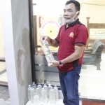 Petugas saat mengamankan minuman keras sebagai barang bukti.