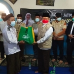 KH. Muhammad Roziqi menyerahkan paket sembako kepada salah satu warga secara simbolis. foto: Yudi Arianto/ bangsaonline.com