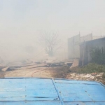 Asap membumbung di gudang kayu UD. Maju Bersama usai terbakar. foto: SYUHUD/ BANGSAONLINE