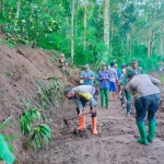 Anggota Polsek dan Koramil Jogorogo bersama warga melakukan kerja bakti membuka jalan yang tertutup longsor.