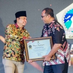 Sekdakab Gresik, Achmad Washil Miftahul Rachman (kanan), menerima piagam penghargaan Menuju Informatif di Anugerah KI Award 2025. Foto: Ist