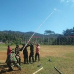 Nampak tiang bendera sedang dinaikkan bersama oleh warga dan TNI. 
