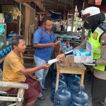 Petugas dari Satlantas Polres Gresik ketika membagikan masker kepada penjual dan pengunjung di warung Terminal Bunder. Foto: SYUHUD/BANGSAONLINE