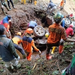 Tim penyelamat saat evakuasi satu unit mobil yang jatuh di jurang akibat tanah longsor di jalan alternatif Kota Batu-Pacet. (Ist)