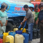 Ketua PWI Lamongan Bachtiar Febrianto mengucurkan air ke drum warga.