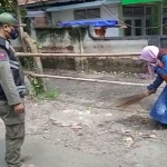 Seorang pelanggar saat menjalani sanksi sosial dengan menyapu di tempat umum. (foto: ist)