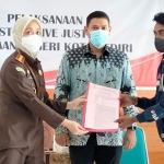 Kepala Kejari Kota Kediri Novika Muzairah Rauf menyerahkan surat ketetapan penghentian penuntutan (SKP2) kepada tersangka Mukamad Effendik disaksikan Wali Kota Abdullah Abu Bakar (tengah). Foto: Ist.