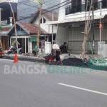 LAMBAT: Pekerja tengah lakukan pengaspalan jalan usai dipasang box culvert di jalan Pangsud, Gresik. foto: syuhud/ BANGSAONLINE