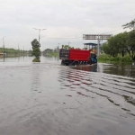 Sebuah truk tampak nekat menerjang banjir di Jalan Raya Porong.