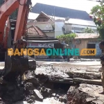 Ekskavator saat melakukan pengerukan untuk pembangunan gorong-gorong. Foto: BAMBANG DWI JULIANTO/BANGSAONLINE