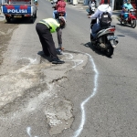 Anggota Satlantas Polres Blitar menandai jalan berlubang mengunakan cat putih.