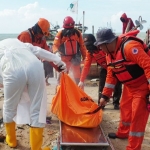 Petugas menyemprotkan disinfektan ke jenazah korban.