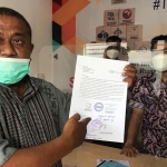 Imam, Ketua Aliansi Masyarakat Peduli Desa Ambulu, saat menunjukkan surat gendom gedung GNI.