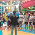 Petugas Polsek Manyar sedang memberikan arahan kepada para pengunjung wisata air Dynasty Water World. foto: SYUHUD/BANGSAONLINE.com