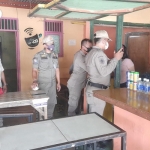 Petugas Satpol PP Gresik ketika menertibkan penjaga warung di Telaga Ngipik. foto: SYUHUD/ BANGSAONLINE.com
