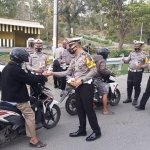 
Kasatlantas Polres Bangkalan, AKP Abdul Aziz Sholahuddin saat menyerahkan buah buahan dan air minum kepada pengendara