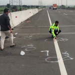 Petugas kepolisian saat melakukan olah TKP di Tol Japanan arah Sidoarjo.