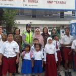 Seorang petugas Polresta Sidoarjo sedang bersama murid-murid salah satu sekolah SD.