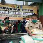 Petugas berbondong-bondong menaruh beras ke truk untuk didistribusikan ke wilayah zona merah Covid-19.