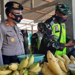 Kapolsek Gampengrejo, AKP Saiful Alam bersama Anggota Koramil Gampengrejo sedang memakaikan masker kepada pedagang pisang. foto: MUJI HARJITA/ BANGSAONLINE