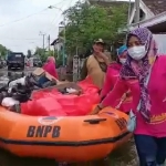 Ibu-ibu warga Desa Gredek Kecamatan Duduksampeyan dengan perahu karet menyalurkan bantuan kepada korban banjir luapan Kali Lamong. foto: ist.