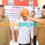 Bupati Gresik, Fandi Akhmad Yani, saat mengenakan helm keselamatan kepada peserta pelatihan kerja. Foto: SYUHUD/BANGSAONLINE