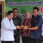 Pemberian potongan tumpeng pertama kepada Lurah Wirolegi (kiri) oleh Camat Sumbersari (kanan) sebagai simbol peresmian Sekolah Perempuan Puspita Legi.