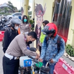 Anggota Satlantas Polres Pasuruan sedang membantu mengisikan BBM gratis kepada seorang pemudik di Pos Pelayanan Taman Dayu, Pandaan.