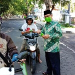 H. Sholeh, Kepala Kemenag Lamongan saat membagikan masker kepada pengendara motor.