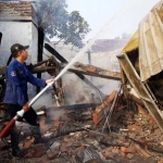 Petugas damkar melakukan pembasahan di TKP. 