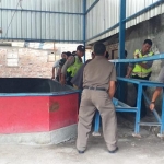 Petugas dibantu warga mengangkut bangku dari besi yang digunakan sebagai tribun untuk menonton sabung ayam.
