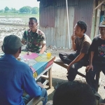 Babinsa Koramil Kenjeran, Serda Budi Hermanto berbincang dengan warga Jalan Memet, Kenjeran.