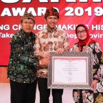 Bupati Jombang, Hj. Mundjidah Wahab menunjukkan piagam SAKIP Award didampingi Wagub Jatim Emil Dardak.