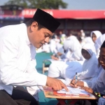Wali Kota Kediri Abdullah Abu Bakar saat melihat salah satu peserta menebal huruf Al-Quran di Stadion Brawijaya Kediri. foto: ARIF K/ BANGSAONLINE
