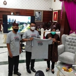 Kepala Staf Kepresidenan Moledoko menyerahkan kaus bertuliskan kampanye pemakaian masker kepada Wali Kota Risma. (foto: YUDI A/ BANGSAONLINE)
